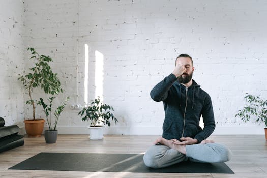 A man in a yoga pose meditating indoors, promoting wellness and relaxation.