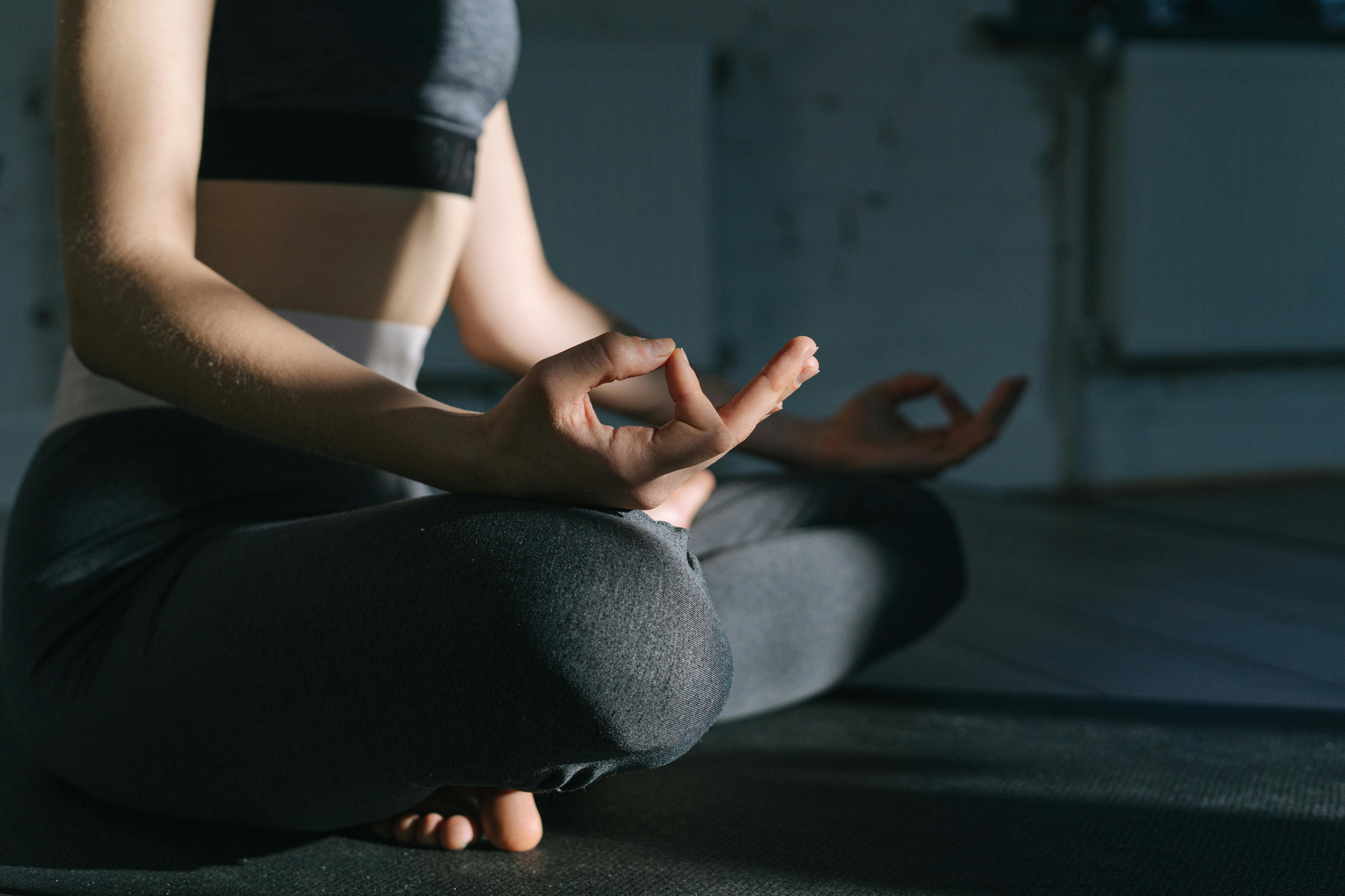 Woman practicing meditation on a yoga mat indoors, focusing on mindfulness and relaxation.