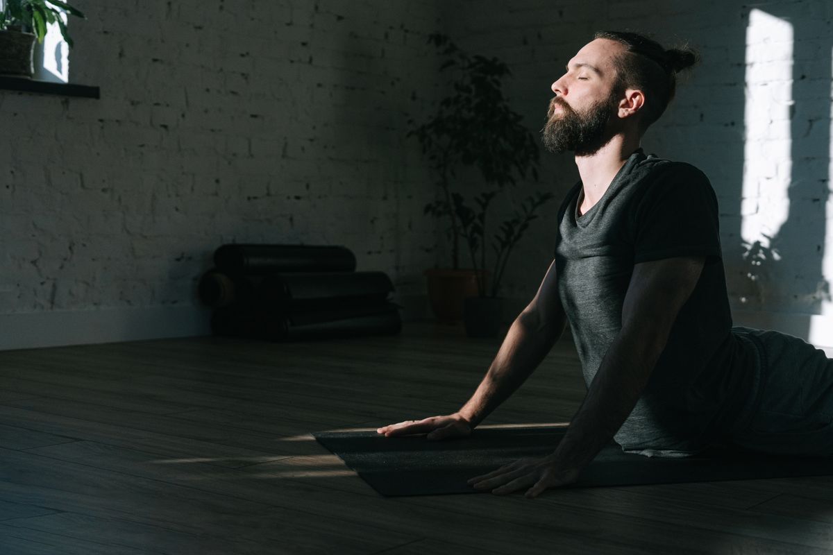 Man sitting on a yoga mat indoors with eyes closed in a calm meditation posture