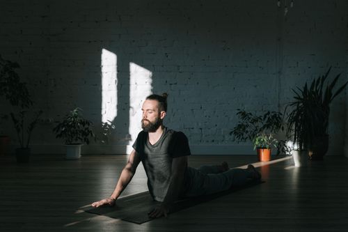 Free A man meditates indoors, bathed in sunlight, promoting tranquility and wellness. Stock Photo