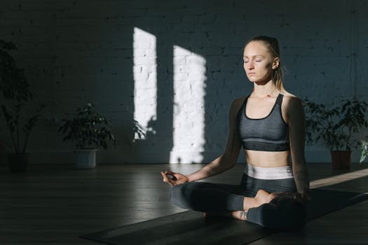 A woman meditates in a serene, sunlit room, embodying focus and tranquility.