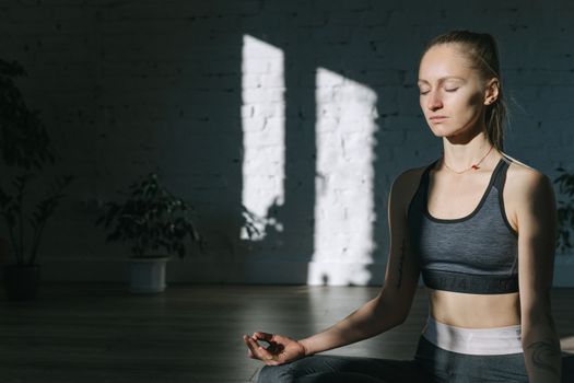 A woman meditates indoors in a serene yoga session, embracing mindfulness and tranquility.