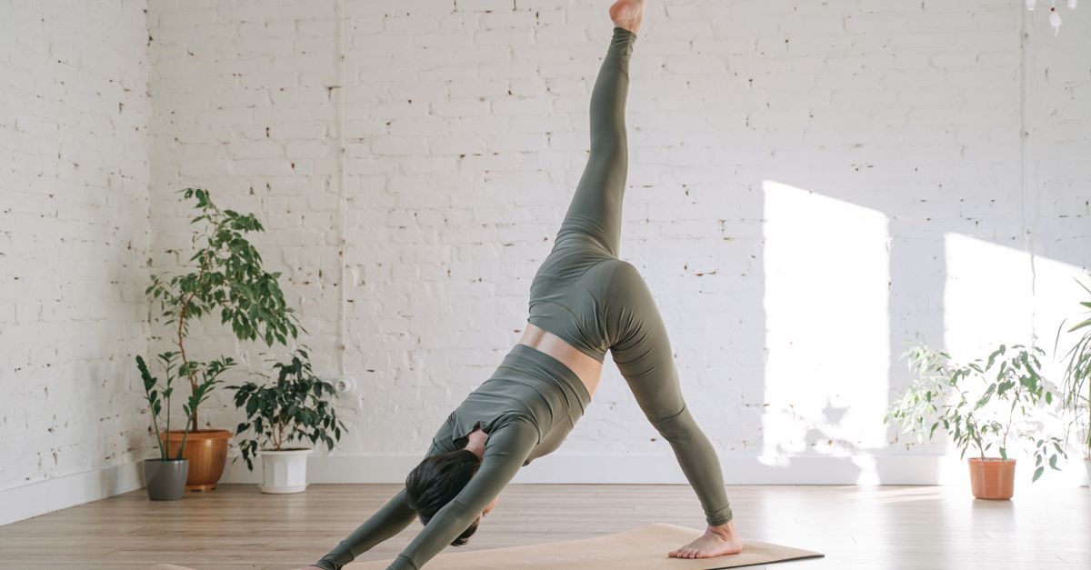 A woman wearing athletic clothes and stretching before a run in a park on a sunny day.