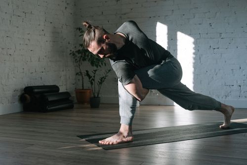 Free Man practicing yoga in a serene indoor environment, focusing on balance and flexibility. Stock Photo
