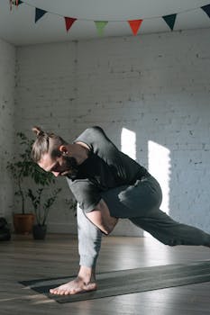 Adult man practicing yoga in a bright indoor studio. Emphasis on balance and wellness.