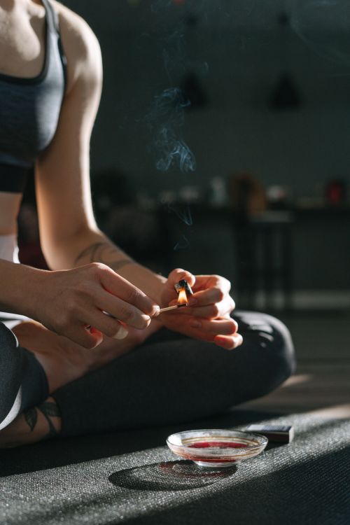 Free A seated individual holding a matchstick, practicing mindfulness indoors with burning incense. Stock Photo