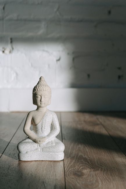A Buddha sculpture in a peaceful setting, illuminated by soft natural light indoors.