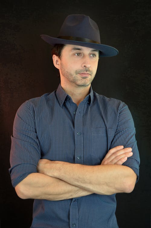 Stylish young guy standing in studio with folded arms