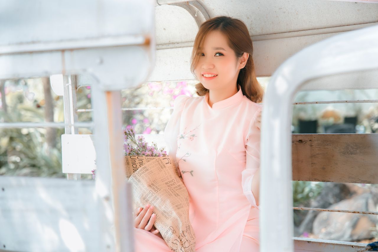 charming woman in pink dress holding a bouquet smiling gracefully in a
