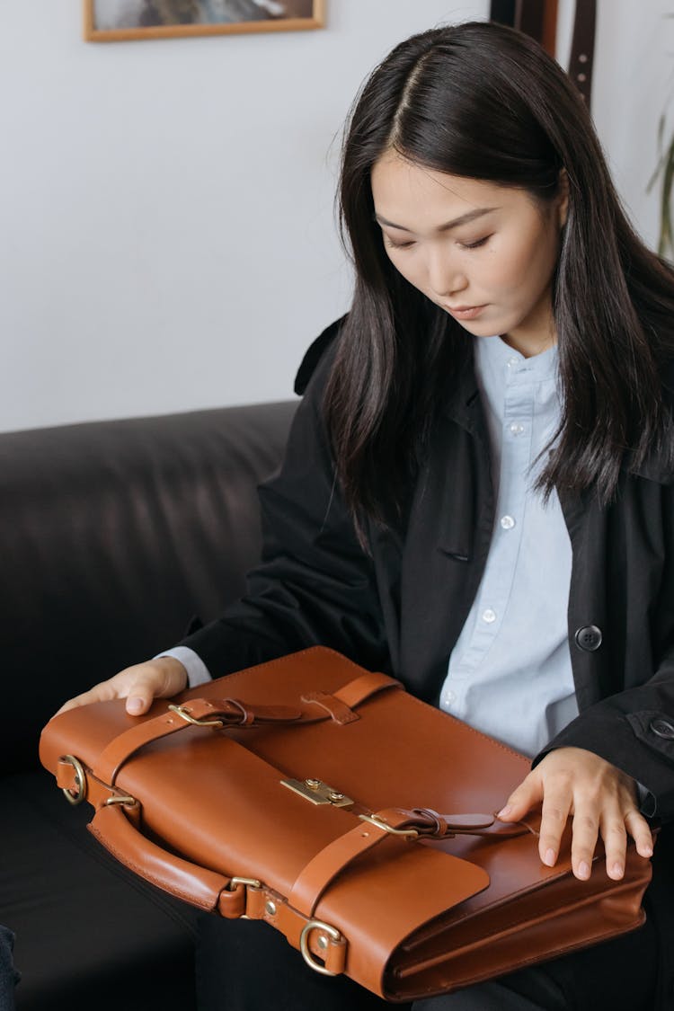 Woman In Black Coat Looking At A Brown Leather Briefcase