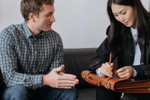 Free Two colleagues discuss business details while seated indoors with a leather briefcase. Stock Photo