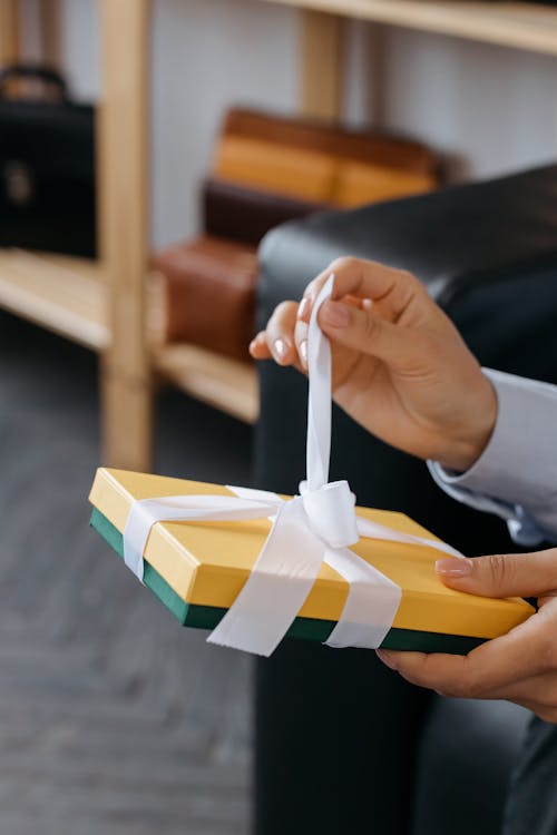 Person holding a brightly wrapped gift box with a white ribbon.