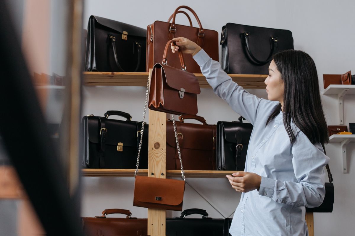 A leather bag held in one hand, strap hanging loose