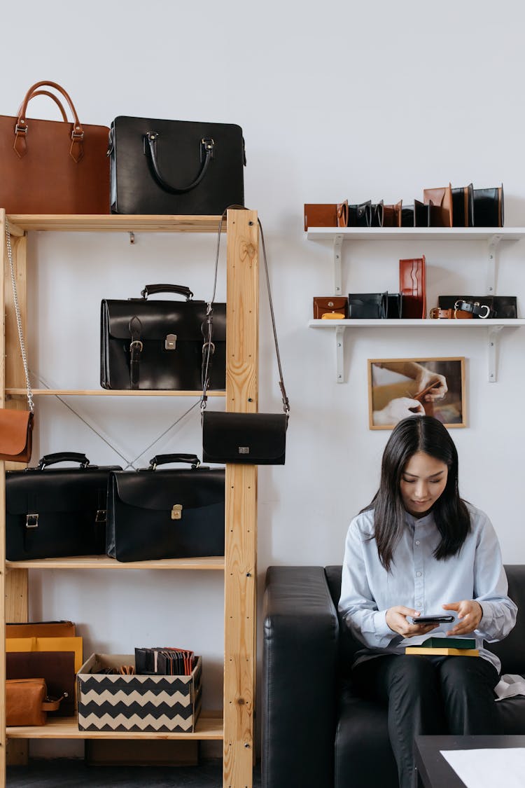 A Woman Sitting In A Leather Bag Store Holding A Purse