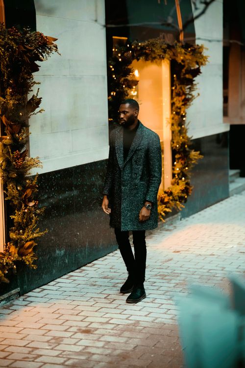 Free Stylish man in coat walking by lit storefront in Ottawa's winter street scene. Stock Photo