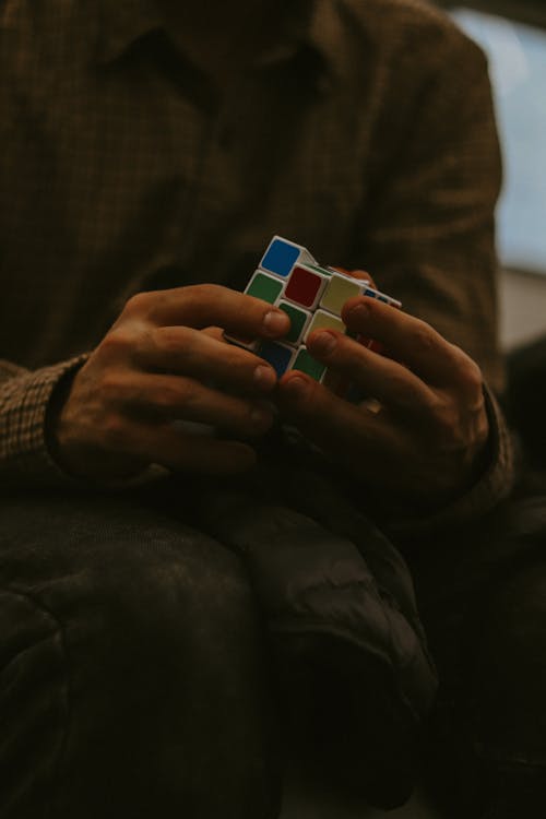 Person Wearing Brown Long Sleeves Holding a Rubic's Cube