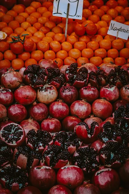 Colorful fruits with pomegranates and mandarins arranged for sale at a market stall.