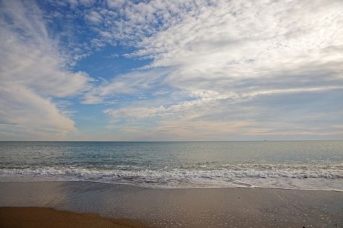 Free Peaceful seascape with calm waves and a cloudy sky meeting the ocean horizon. Stock Photo