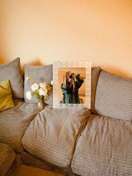 A woman captures her reflection while taking a mirror selfie on a comfortable sofa at home.