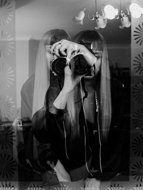 Artistic double exposure of a woman with a camera in monochrome, creating a layered effect.