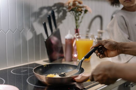Close-up of frying eggs on an induction stove during morning breakfast preparation.