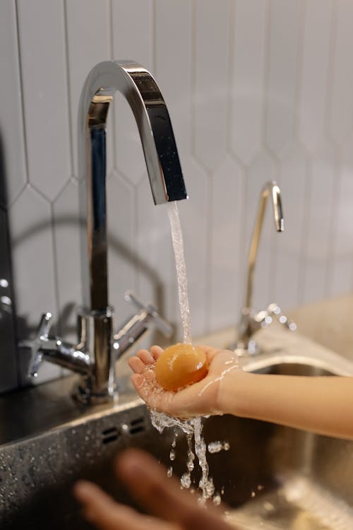 Free Close-Up Shot of a Person Washing an Egg on Running Water Stock Photo