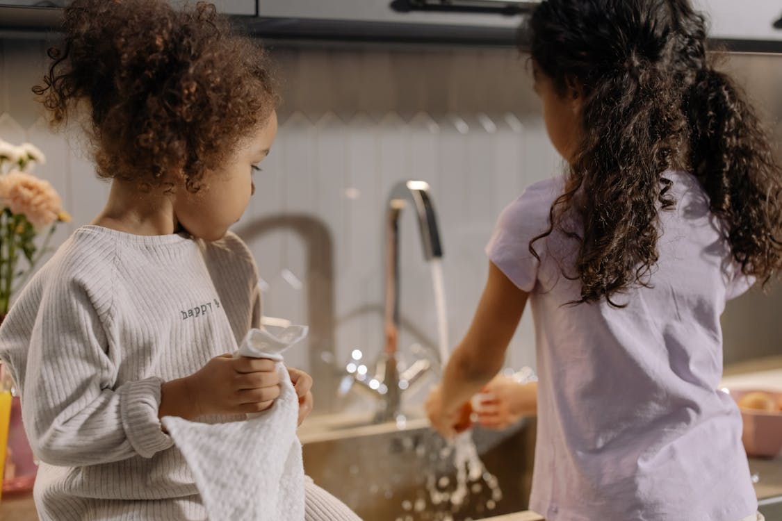 Back View of Sisters Helping in Household Chore