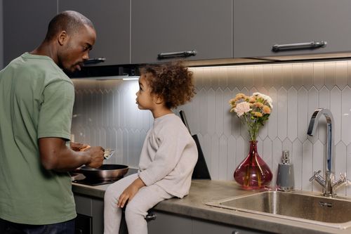 Free A father and daughter bonding while cooking together in a modern kitchen. Stock Photo