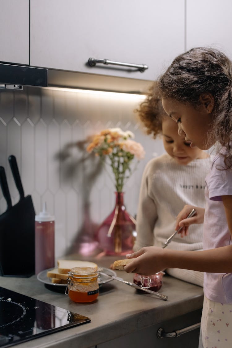 Two Girls Making Jam Sandwiches