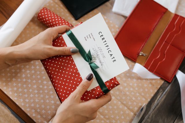 Hands holding a ribboned gift certificate — photo by cottonbro studio on Pexels