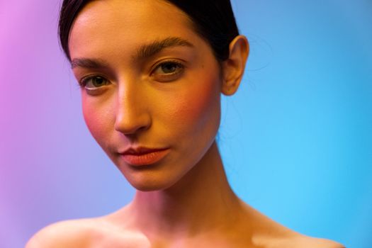 A woman in a studio with captivating neon lighting, showcasing beauty and elegance.