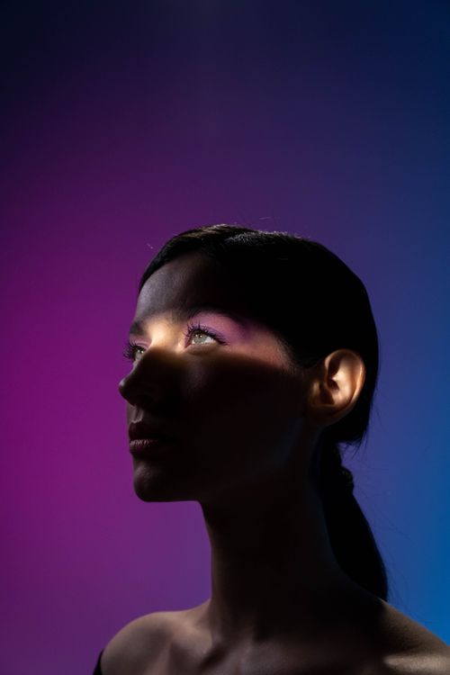 Free Moody studio portrait of a woman with purple and blue lighting. Stock Photo