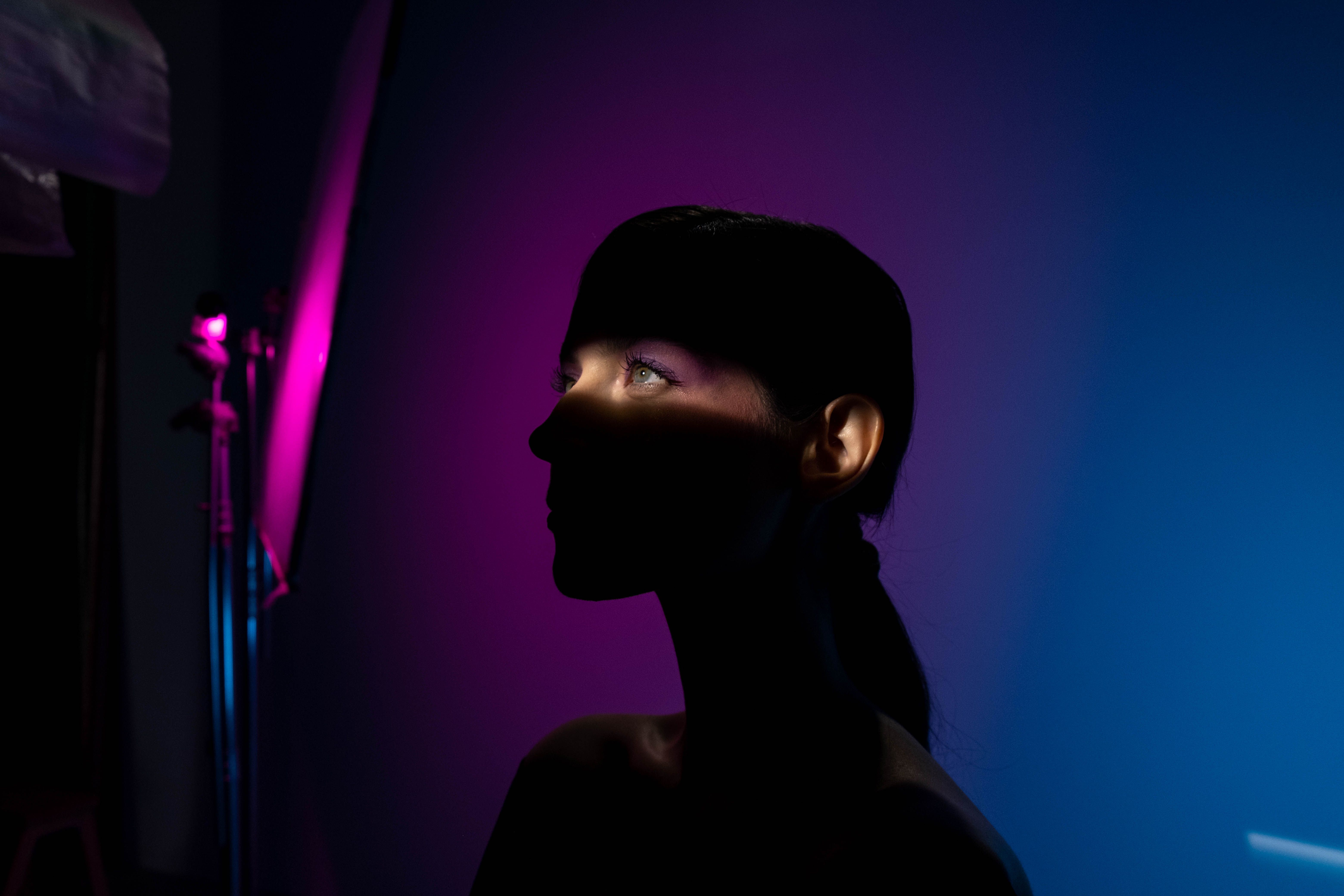 Artistic silhouette of a woman with vivid pink and blue lighting creating dramatic shadows.