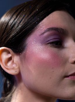 A close-up shot capturing a woman's glittery makeup and vibrant eyeshadow.