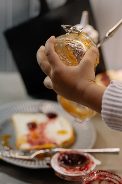 Free A child is seen spreading jam on a slice of toast, enhancing a delicious breakfast or snack scene. Stock Photo