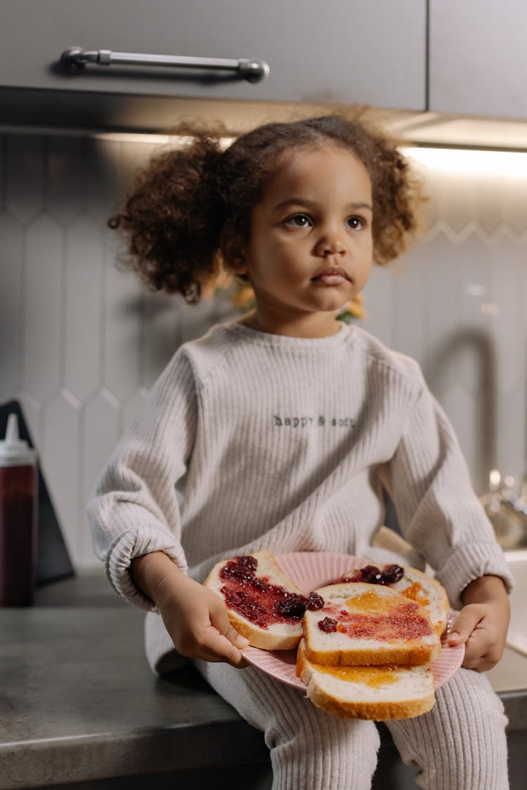 A Girl Holding A Plate Of Sandwich With Strawberry Jam