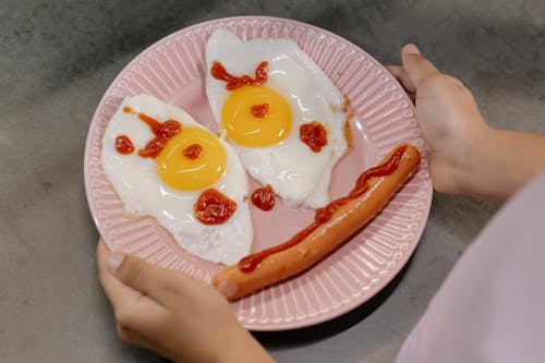 Free A Smiley on a Plate Made of Sunny Side Up Eggs and a Sausage Stock Photo
