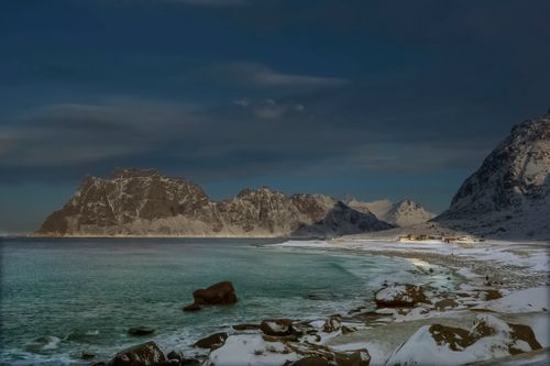 Free Snowy landscape at Uttakleiv Beach, Norway with snowcapped mountains under a moody winter sky. Stock Photo