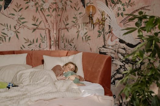A woman peacefully sleeping in a beautifully decorated bedroom with floral wallpaper.