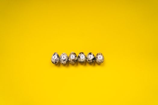 Quail eggs with letters spelling Easter on a bright yellow background, minimalist style.