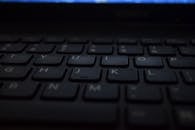 在昏暗的灯光下，特写镜头展示了现代笔记本电脑键盘的技术与设计