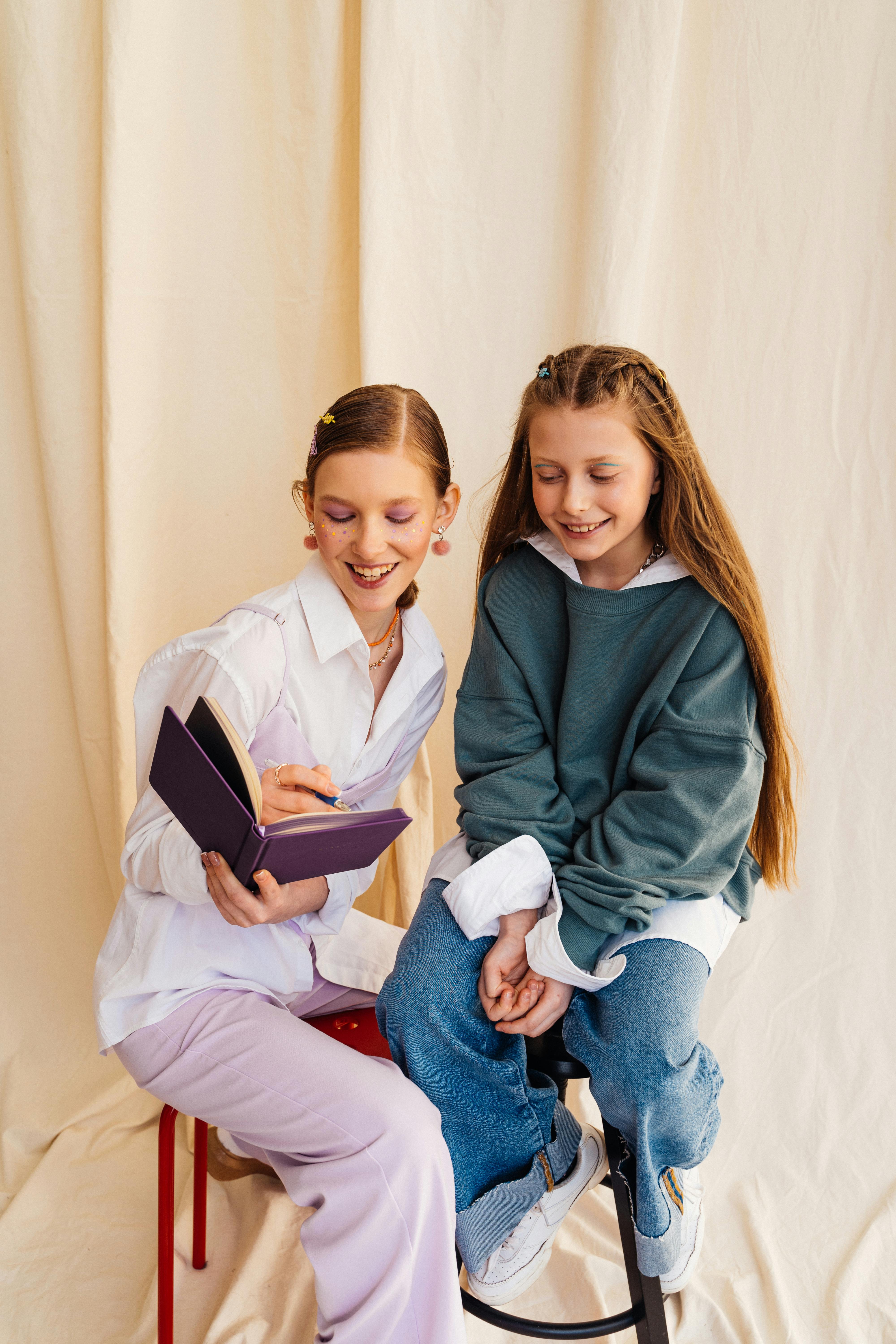 girls sitting on stools and holding a book