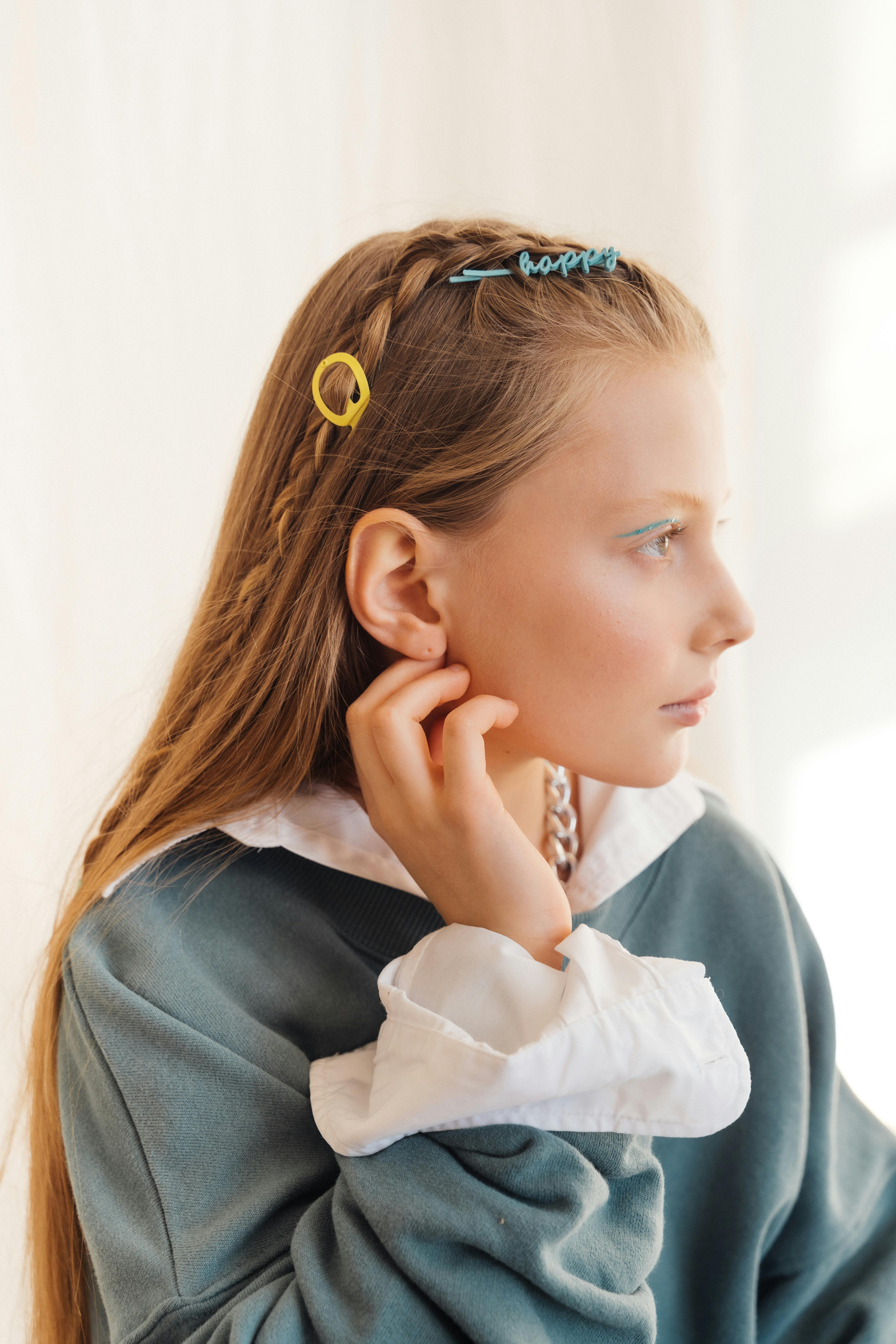 Stylish adolescent girl with hair clips in a side view portrait indoors.