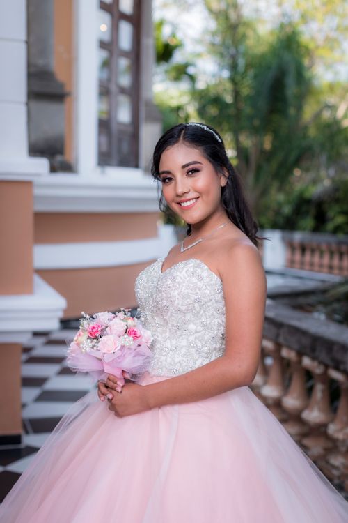 Free Beautiful bride in a stunning bridal gown smiling while holding a bouquet outdoors. Stock Photo