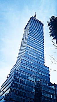 Striking low-angle view of a high-rise glass skyscraper in Mexico City under a clear sky.