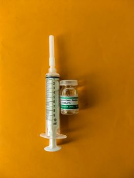 Detailed image of a COVID-19 vaccine vial and syringe on a vibrant background.