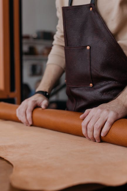 Close-up of hands rolling leather in a craftsman's workshop, emphasizing skill and craftsmanship.
