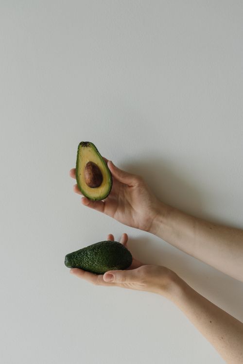 Free A minimalist shot showcasing hands holding a cut avocado, emphasizing healthy eating choices. Stock Photo