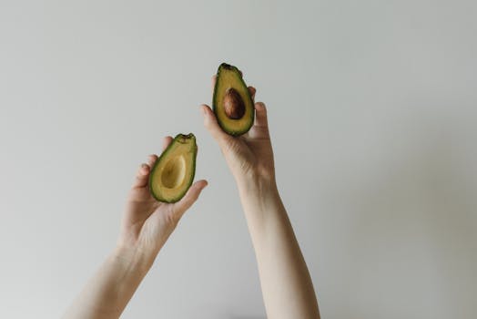 Close-up of hands holding a fresh sliced avocado, highlighting healthy eating.