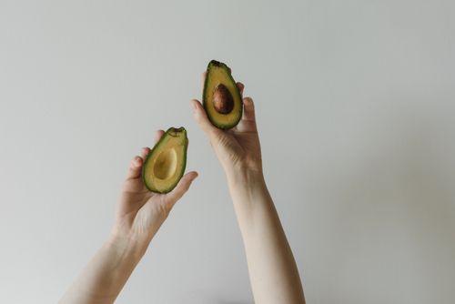 Free Close-up of hands holding a fresh sliced avocado, highlighting healthy eating. Stock Photo